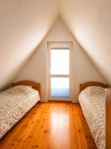 two beds in a attic bedroom with a window at Zacisze nad Jeziorem- prywatny domek blisko morza in Jezierzany