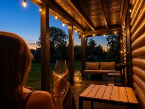 a woman holding a glass of wine on a patio at Zacisze nad Jeziorem- prywatny domek blisko morza in Jezierzany
