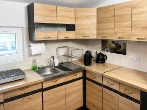 a kitchen with wooden cabinets and a sink at Zacisze nad Jeziorem- prywatny domek blisko morza in Jezierzany +13 photos