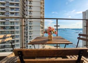 a wooden table with a vase of flowers on a balcony at Amberside Coastal Breeze Oasis in Johor Bahru