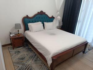 a bed with a blue headboard in a bedroom at Intercultural Apartment Nairobi Two Rivers in Nairobi +29 photos