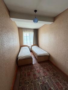a small room with two beds and a window at M-otel in Karakol