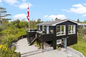 a black house with a flag on top of it at 8528-Grenaa-Klitten-28 in Grenå