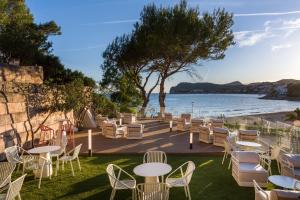a group of tables and chairs next to a body of water at Hotel Vibra Beverly Playa in Paguera