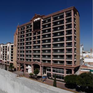 a large building on a street in a city at Hotel Real Plaza Aguascalientes in Aguascalientes