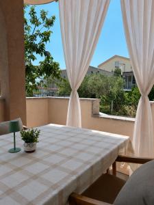 a table with white curtains in a room with a window at Apartman LaVida in Kaštela