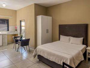 a bedroom with a bed and a table and a kitchen at Cosmo Sleepover in Roodepoort