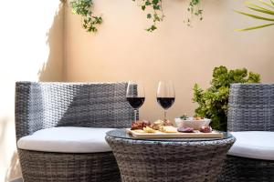 two wicker chairs with a table with a plate of food and wine glasses at Aurà Guest House Iblea in Ragusa