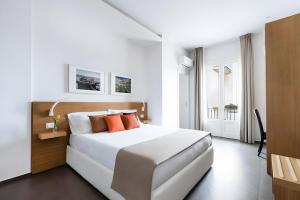 a white bedroom with a white bed with orange pillows at Aurà Guest House Iblea in Ragusa