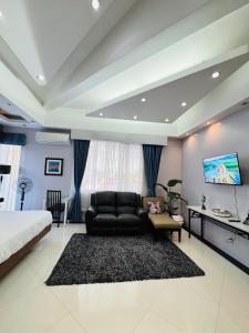 a living room with a black couch and a tv at Anavada Suites - Davao City in Davao City