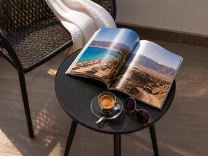 a table with a book and a cup of coffee and glasses at La Coquille - הקונכייה in Eilat