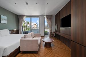 a hotel room with a bed and a chair and a tv at MAIA Boutique Hotel Da Nang in Danang