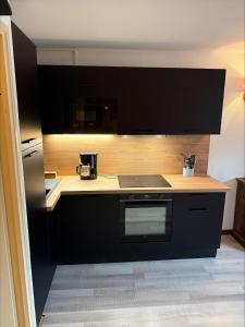 a kitchen with black cabinets and a stove top oven at Chez Arthur et Léa in La Joue du Loup