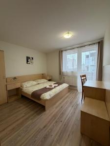 a bedroom with a bed and a desk and a window at Guest house Fleurs in Liptovský Mikuláš