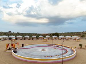 a pool in the middle of a beach with umbrellas at Rumis Desert Camp in Jaisalmer