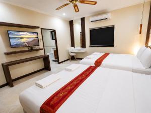 a bedroom with two beds and a flat screen tv at Phratamnak Seaside Pool Villa in Pattaya South