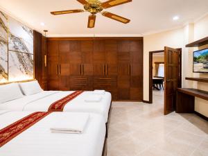 a bedroom with two beds and a ceiling fan at Phratamnak Seaside Pool Villa in Pattaya South
