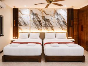two beds in a bedroom with a painting on the wall at Phratamnak Seaside Pool Villa in Pattaya South