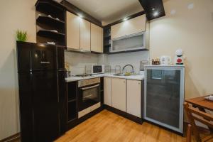 a kitchen with a black refrigerator and white cabinets at Iglika Beach in Golden Sands