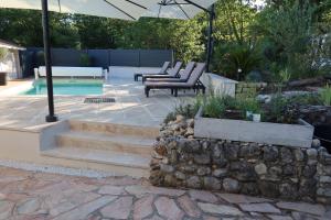 a patio with a stone wall and stairs next to a pool at La Vilo Dòu Verdon in Roumoules