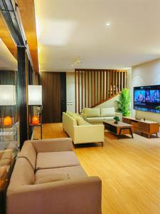 a living room with two couches and a flat screen tv at The LakeFront Villa in Binangonan