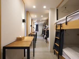 a hallway with bunk beds and a wooden table at Piece Hostel Kyoto in Kyoto