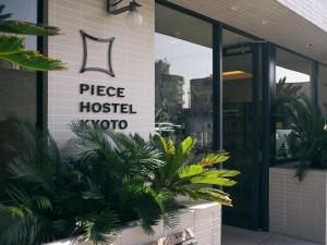 a sign on the side of a building with plants at Piece Hostel Kyoto in Kyoto