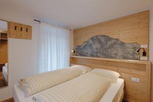a bedroom with a bed with a wooden wall at Appartamento Aurone - con Biosauna in Arabba