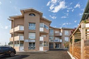 an apartment building with a car parked in front at Appartement Les Jardins in Saint-Vincent-de-Tyrosse