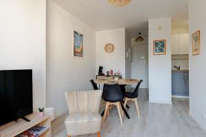 a living room with a table and chairs and a television at Appartement Les Jardins in Saint-Vincent-de-Tyrosse