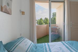 a bedroom with a bed and a sliding glass door at Appartement Les Jardins in Saint-Vincent-de-Tyrosse