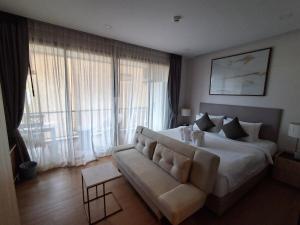 a large bedroom with a white bed and a couch at Rawai Sea Escape 1BR With Rooftop Pool in Rawai Beach +26 photos