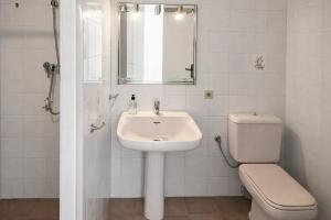 a white bathroom with a sink and a toilet at La Casa de la Punta in San Pol de Mar