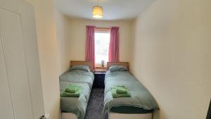 two beds in a small room with a window at Stornoway Stays Apartment in Stornoway