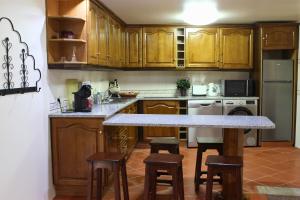a kitchen with wooden cabinets and a marble counter top at Casa Moinho da Levada - Refúgio à beira do rio Coura in Paredes de Coura +17 photos