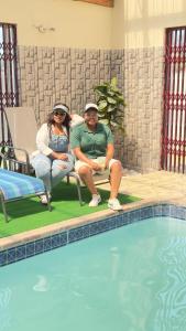 two people sitting in chairs next to a swimming pool at Hendrinas Guesthouse in Hendrina