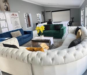 a living room with white couches and a green couch at Hendrinas Guesthouse in Hendrina