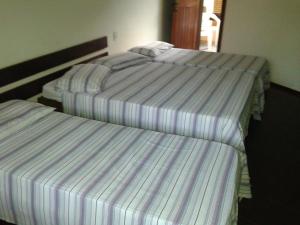 3 posti letto in una stanza con lenzuola a righe di Pousada Vila Verde a Olivença Altre 20 foto