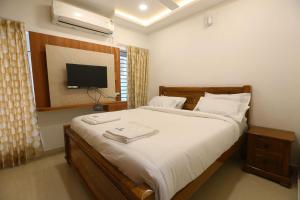 a bedroom with a large bed with a tv on the wall at SR Castle Gopalapuram in Chennai