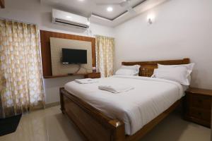 a bedroom with a large bed and a television at SR Castle Gopalapuram in Chennai +18 photos