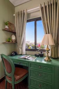 a green desk with a window and a lamp at Vina Classic Hotel in Hue