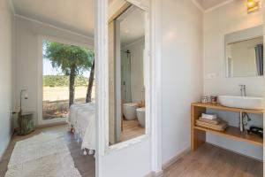 a bathroom with a large mirror and a bed and a sink at Macondo Agriliving Tiny Houses in Castiadas +54 photos
