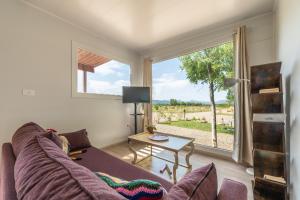 a living room with a couch and a large window at Macondo Agriliving Tiny Houses in Castiadas
