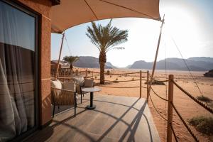 a patio with a table and a palm tree in the desert at Valley Resort in Wadi Rum
