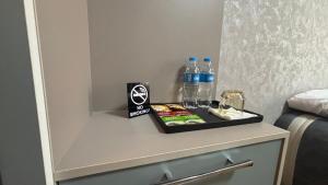 a nightstand with bottles of water and a box of cigarettes at Over City Hostel in Margilan +35 photos