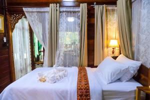 a bedroom with a bed with white sheets and a window at Chom Wat Boutique Hotel in Ban Hau Chang