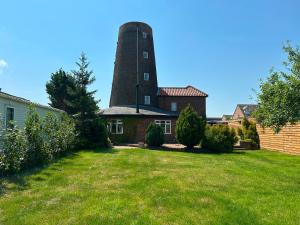 a house with a tower on top of a yard at The Windmill by TJ Serviced Property in Farcet