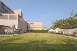 a large grassy yard with umbrellas in front of a building at ACASA Collective in Aurangabad