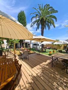 a wooden deck with tables and umbrellas at Logis Hôtel Synaya in Sanary-sur-Mer