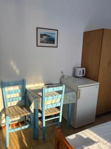a table with two chairs and a small refrigerator at Faros Rooms Armenistis in Armenistis